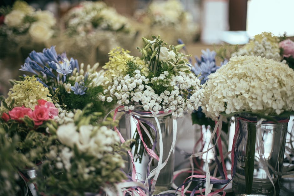 A collection of floral arrangements featuring white hydrangeas with dense, rounded clusters of small petals, delicate white baby's breath with tiny blooms, and bluebell-shaped flowers in soft purple h